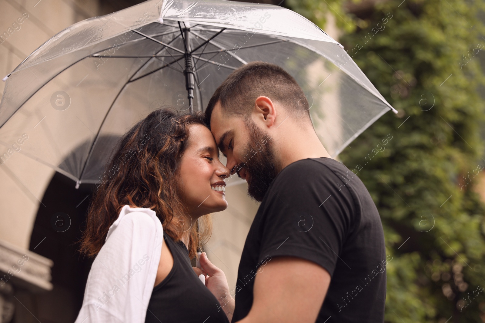 Photo of Young couple with umbrella enjoying time together under rain on city street