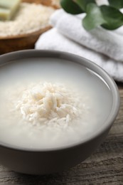 Photo of Bowl with rice soaked in water on wooden table, closeup