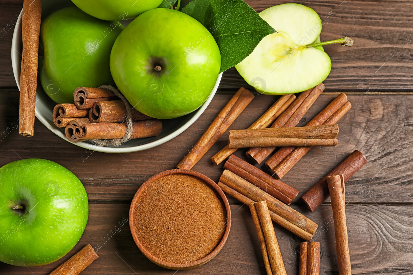 Photo of Fresh apples with cinnamon sticks and powder on wooden table, top view