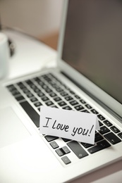 Photo of Note with handwritten text I Love You on laptop. Romantic message