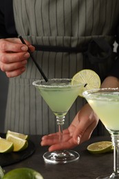 Woman making delicious Margarita cocktail at grey table, closeup