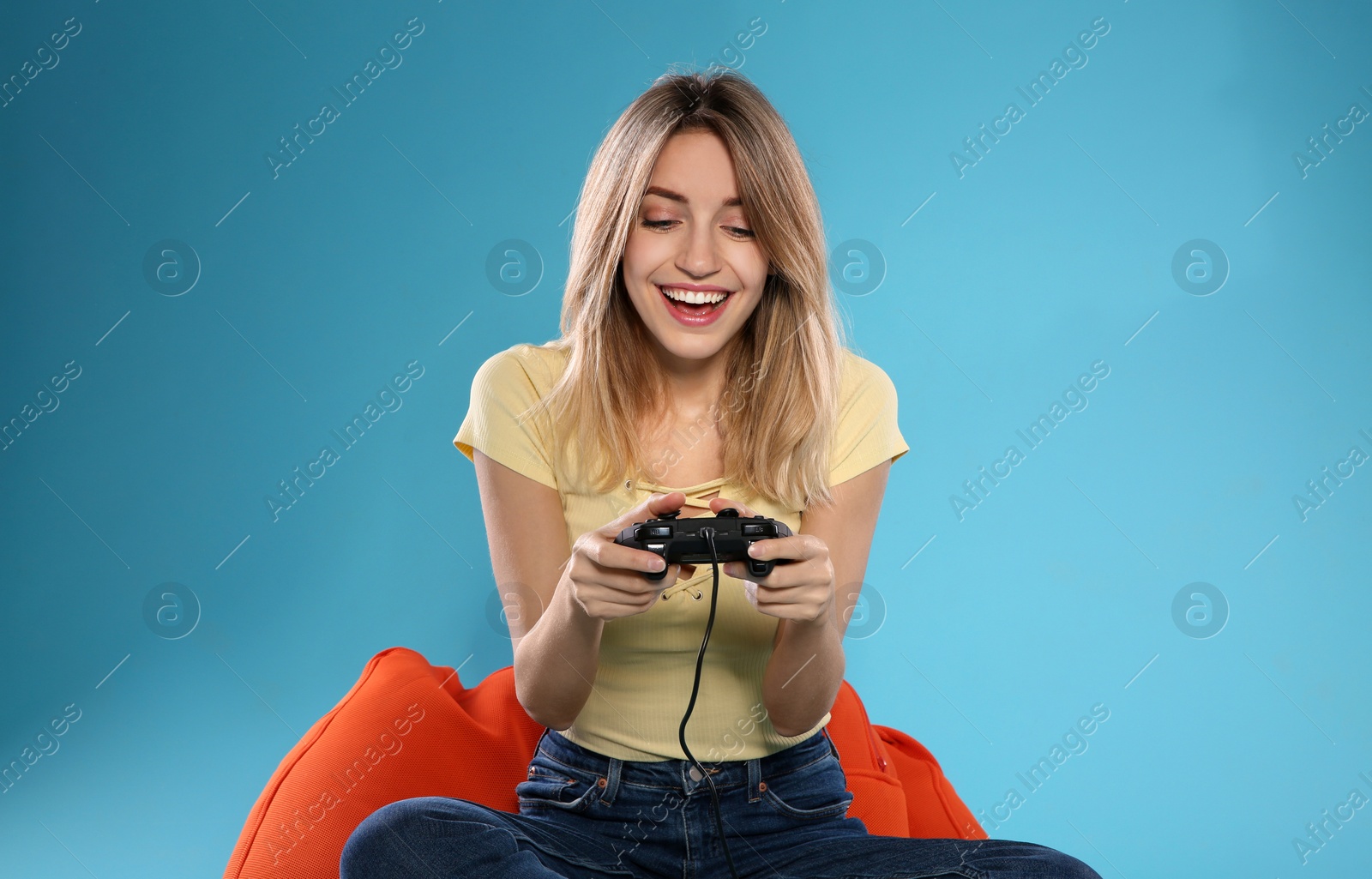 Photo of Emotional young woman playing video games with controller on color background