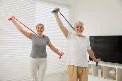 Photo of Senior couple doing exercise with fitness elastic bands at home