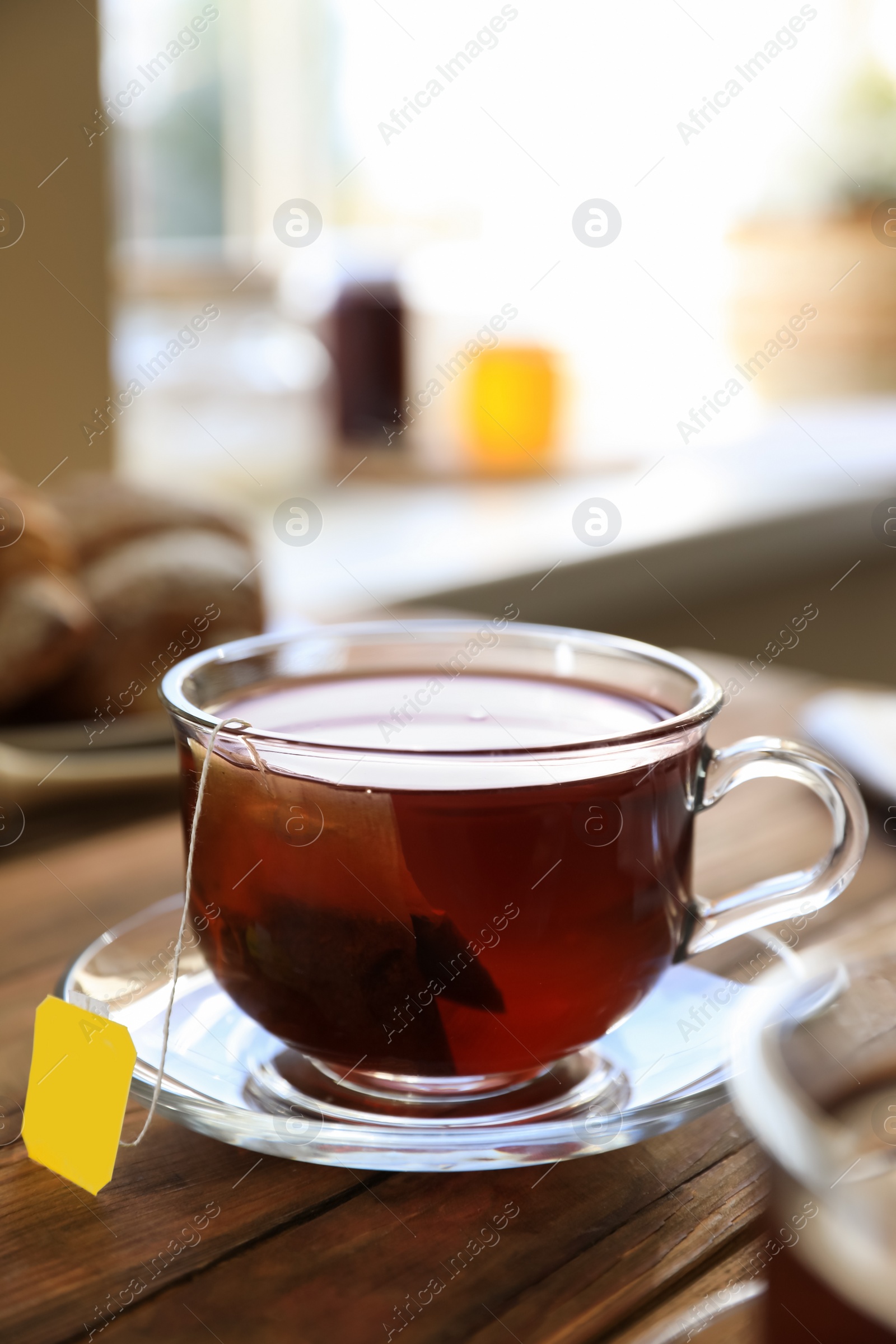 Photo of Tea bag in glass cup on wooden table indoors, closeup