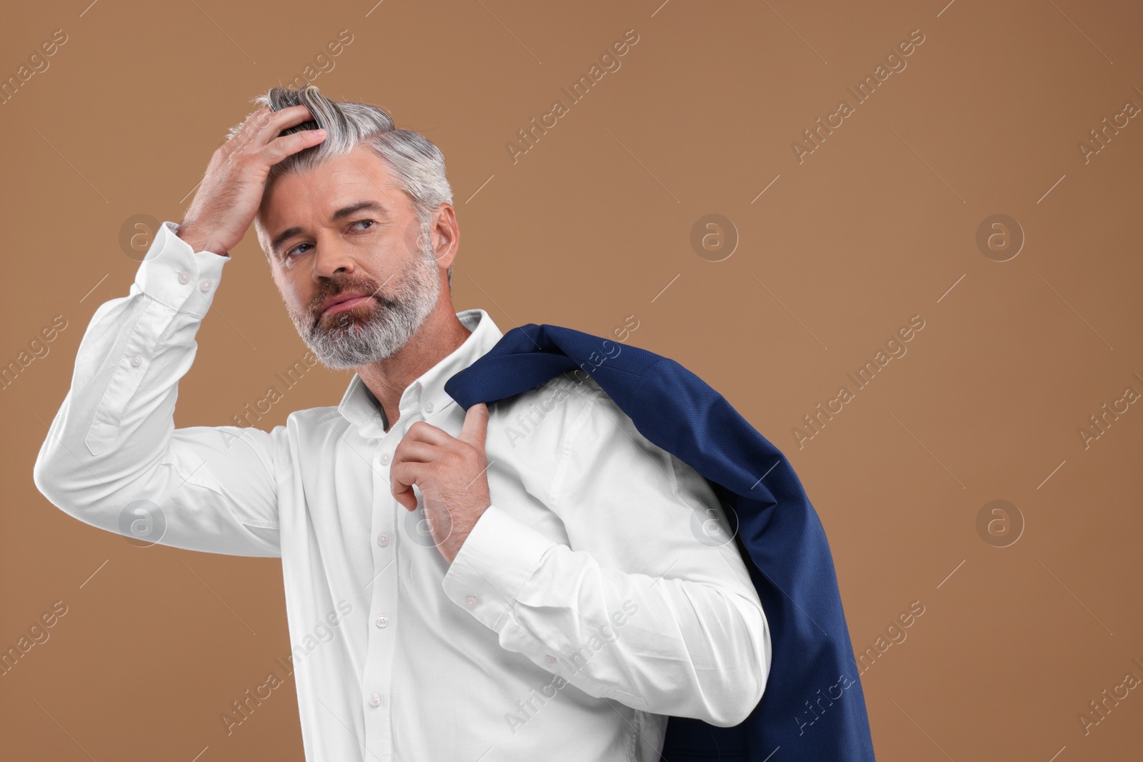 Photo of Portrait of confident man with beautiful hairstyle on light brown background. Space for text