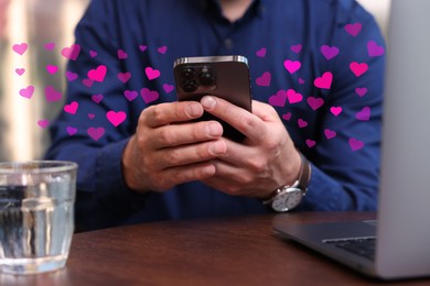 Long distance love. Man sending or receiving text message at table, closeup. Hearts flying out of device