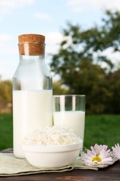 Tasty fresh milk and cottage cheese on wooden table outdoors