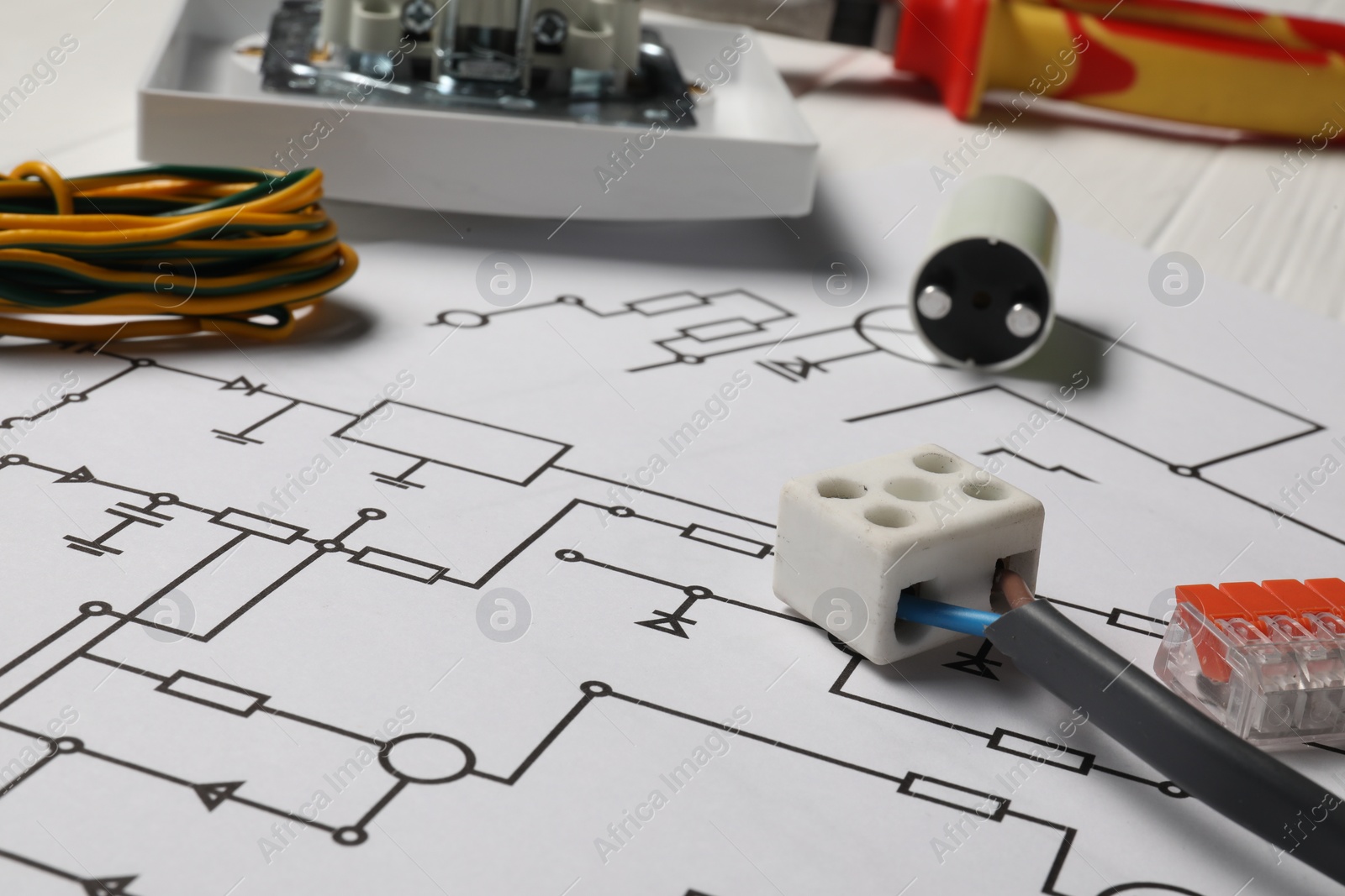 Photo of Wiring diagram, wires and digital multimeter on white table, closeup