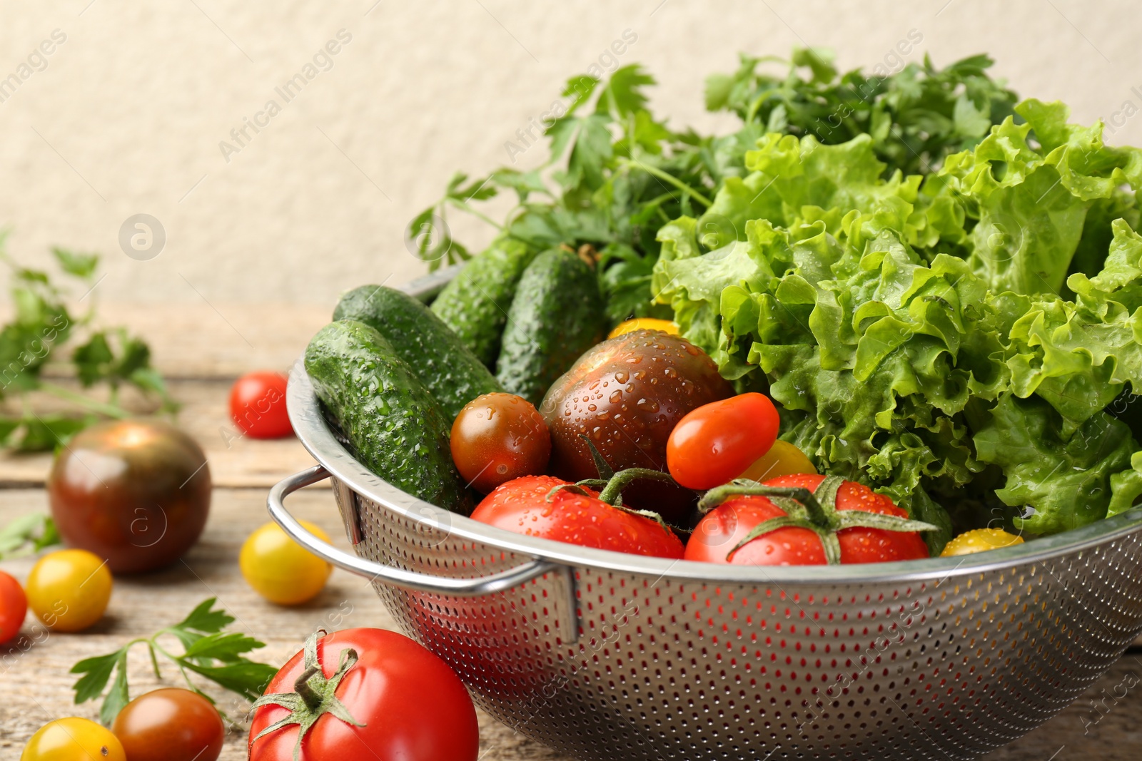 Photo of Wet vegetables in colander on wooden table, closeup