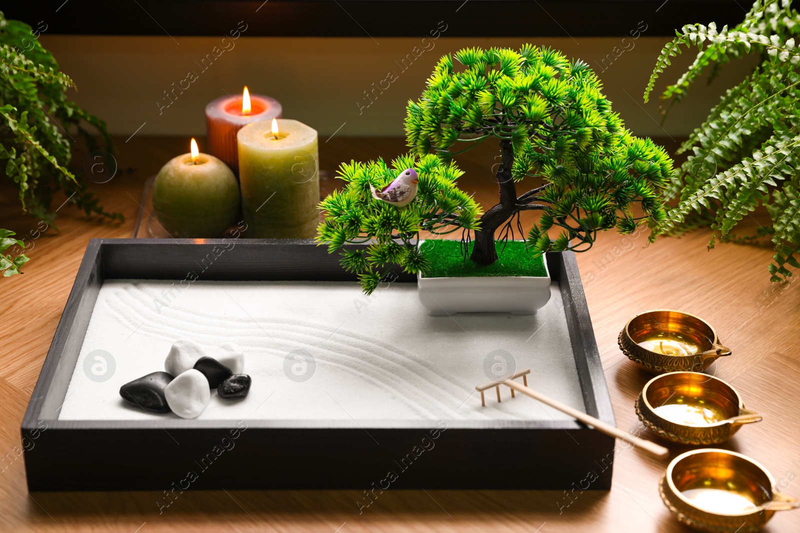 Photo of Beautiful miniature zen garden, candles and oil lamps on table