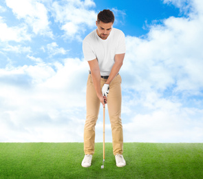 Young man playing golf on course with green grass against blue sky