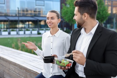 Photo of Smiling business woman talking with her colleague during lunch outdoors