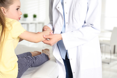 Photo of Professional orthopedist examining little patient's arm in clinic