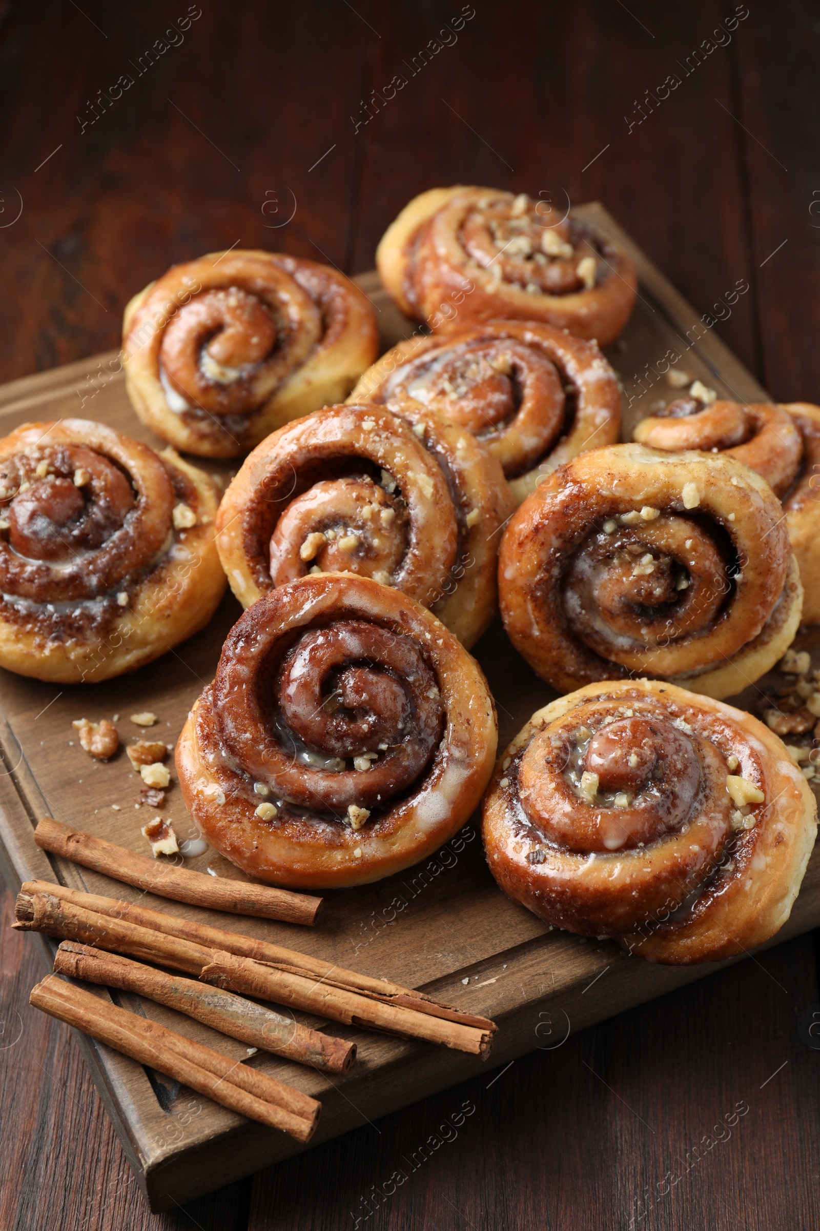 Photo of Tasty cinnamon rolls, sticks and nuts on wooden table