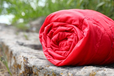 Rolled sleeping bag outdoors on sunny day, closeup