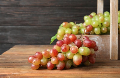 Photo of Fresh ripe juicy grapes on table against blurred background with space for text