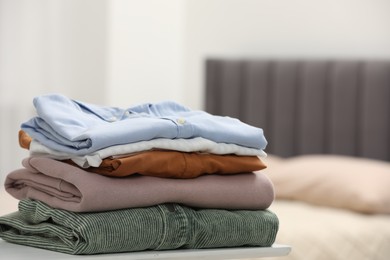 Photo of Stack of different folded clothes on table indoors, closeup. Space for text