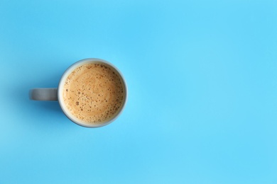 Photo of Cup of coffee on blue background, top view. Space for text