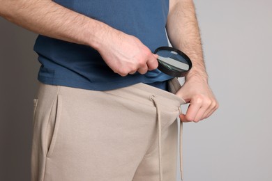 Photo of Man examining genital herpes with magnifying glass on beige background, closeup.