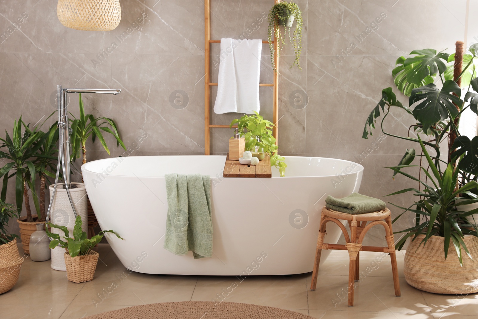 Photo of Modern white tub and beautiful green houseplants in bathroom. Interior design