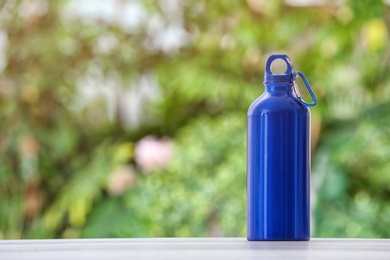 Photo of Sports water bottle on table against blurred background. Space for text