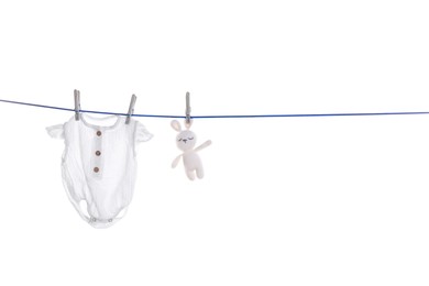Photo of Baby onesie and toy bunny drying on laundry line against white background