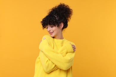 Photo of Happy young woman in stylish warm sweater on yellow background