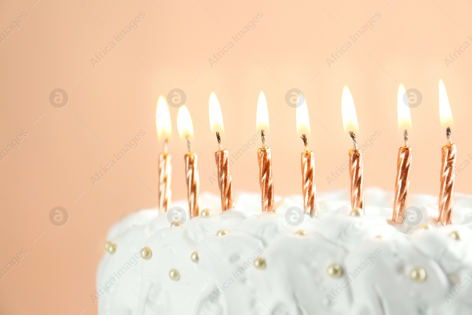 Photo of Birthday cake with burning candles on beige background, closeup