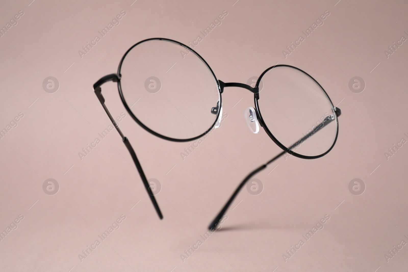 Photo of Stylish pair of glasses with black frame on pale brown background