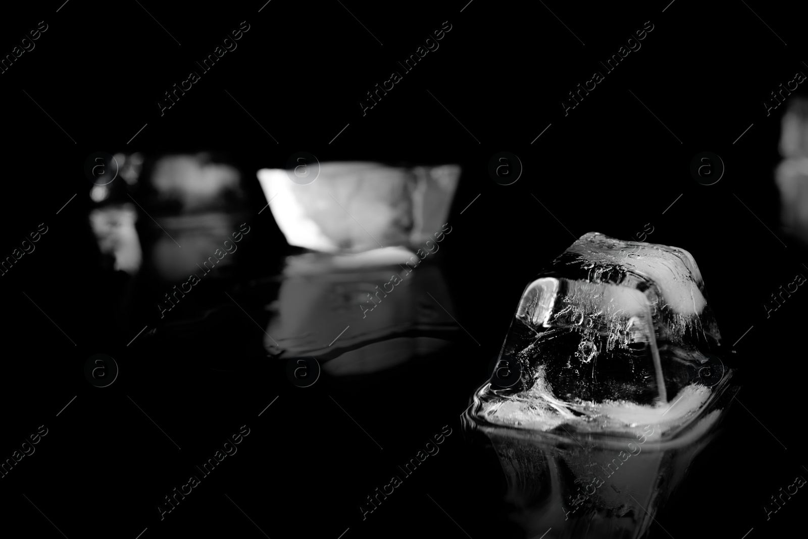 Photo of Ice cube on black mirror surface. Space for text