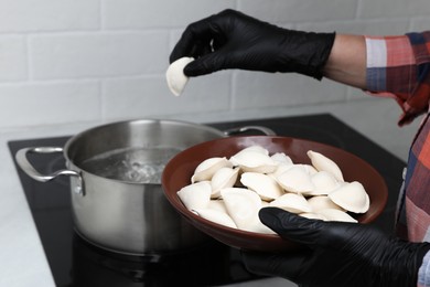 Photo of Woman cooking delicious dumplings in kitchen, closeup