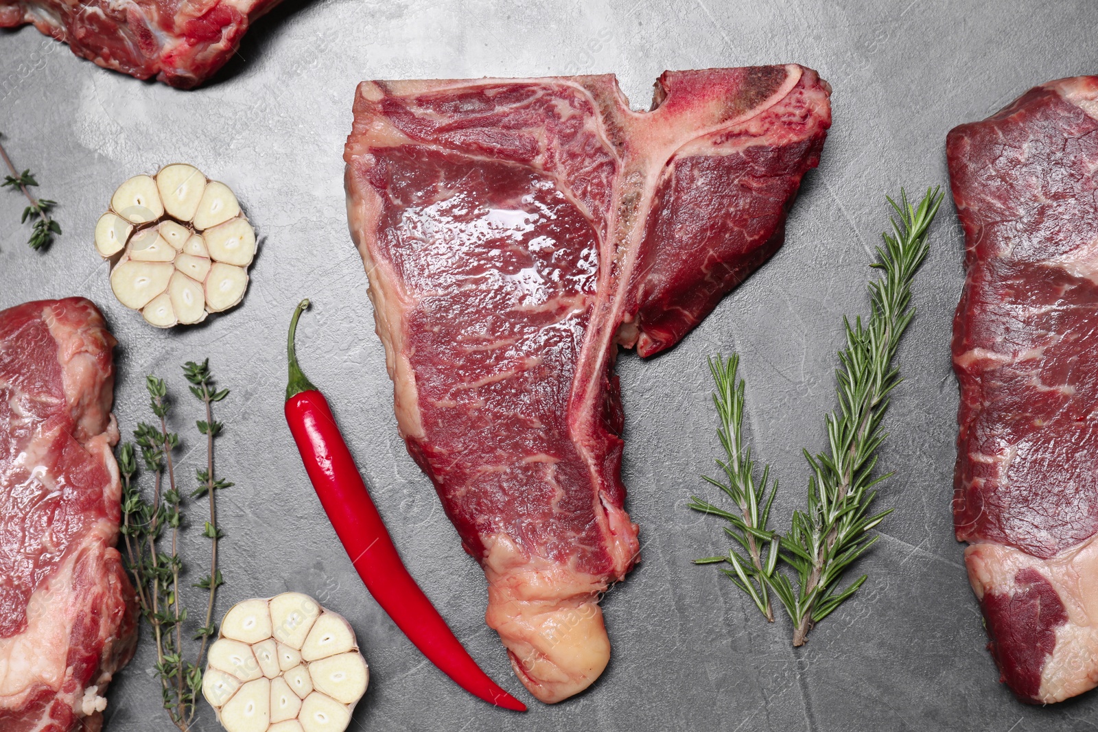 Photo of Fresh raw beef cuts and different spices on light grey textured table, flat lay