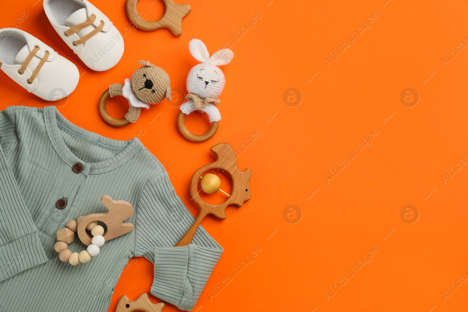 Photo of Flat lay composition with baby clothes and accessories on orange background, space for text