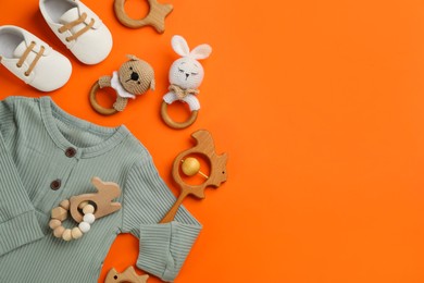 Photo of Flat lay composition with baby clothes and accessories on orange background, space for text