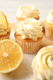 Photo of Tasty cupcakes with cream and lemon zest on board, closeup