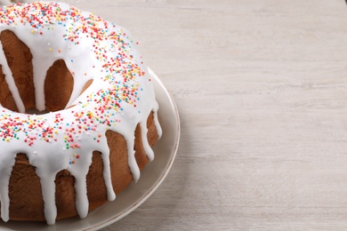 Glazed Easter cake with sprinkles on white wooden table, closeup. Space for text