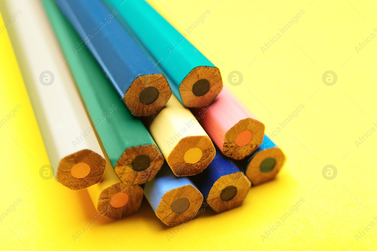 Photo of Different color pencils on yellow background, closeup