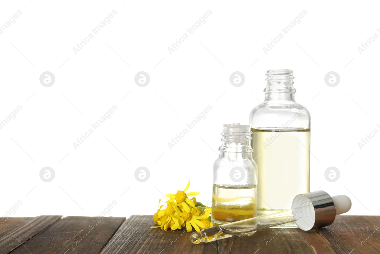 Photo of Bottles of herbal essential oils, pipette and flowers on wooden table, white background