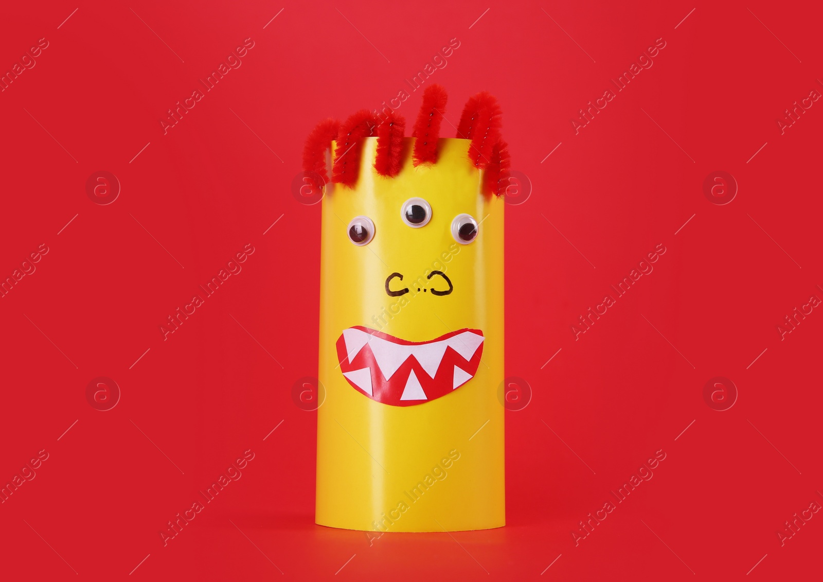Photo of Funny yellow monster on red background. Halloween decoration