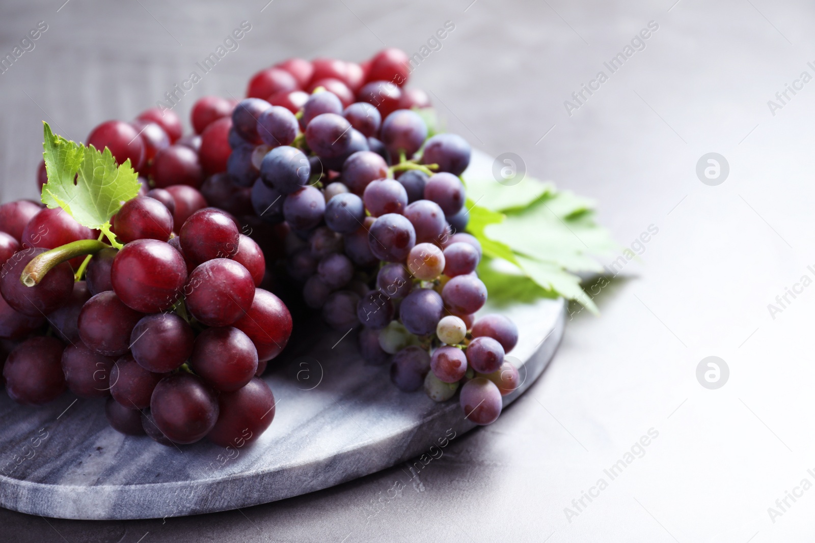 Photo of Fresh ripe juicy grapes on grey table