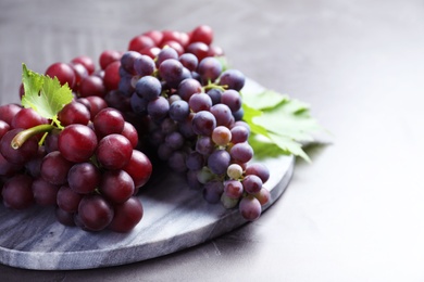 Fresh ripe juicy grapes on grey table