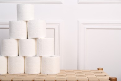 Photo of Pyramid of toilet paper rolls on wicker bench. Space for text