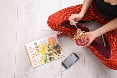 Photo of Young woman in fitness clothes having healthy breakfast at home, top view