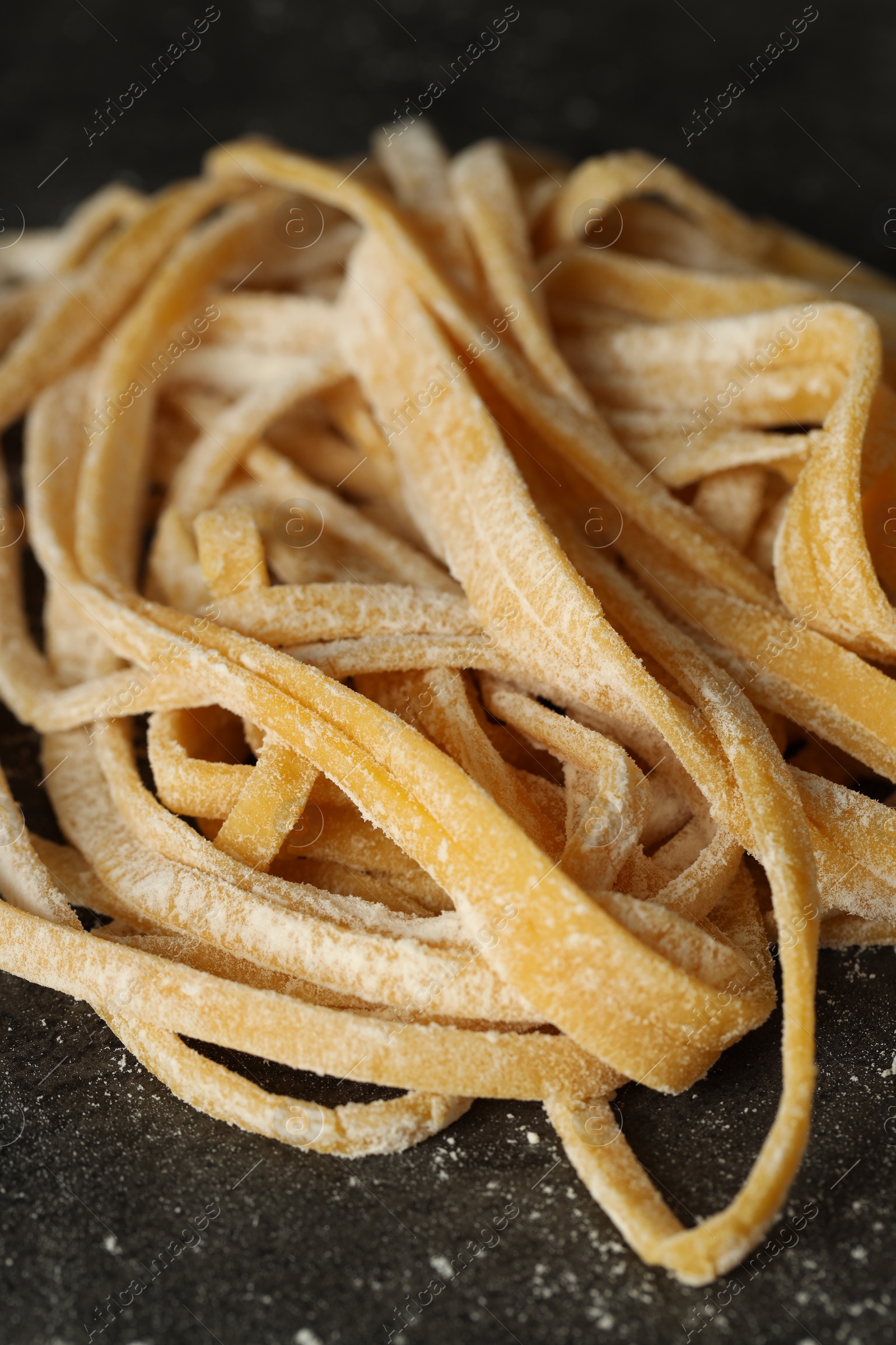 Photo of Uncooked homemade pasta on dark grey table, closeup