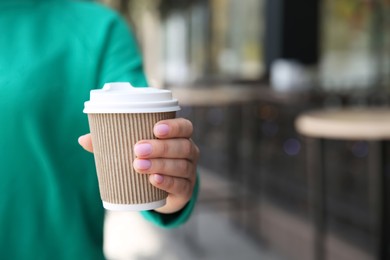 Woman with takeaway coffee cup outdoors, closeup. Space for text