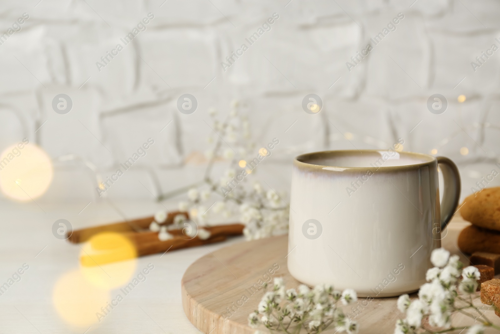 Photo of Cup of hot beverage and flowers on white wooden table, bokeh effect. Space for text