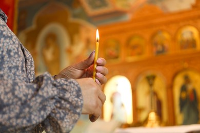 Photo of Mature woman holding candle in church, closeup. Space for text