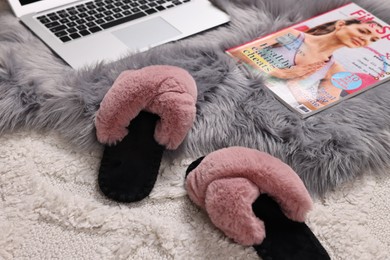 Photo of Soft slippers, magazine and laptop on carpet, closeup