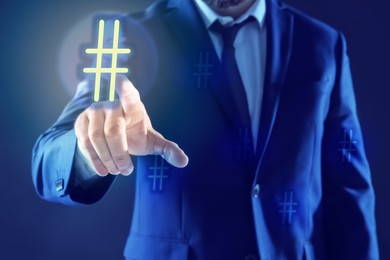 Image of Hashtag concept. Man pointing at sign on blue background, closeup