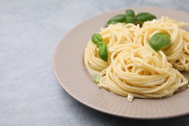 Photo of Delicious pasta with brie cheese and basil leaves on grey textured table, closeup. Space for text